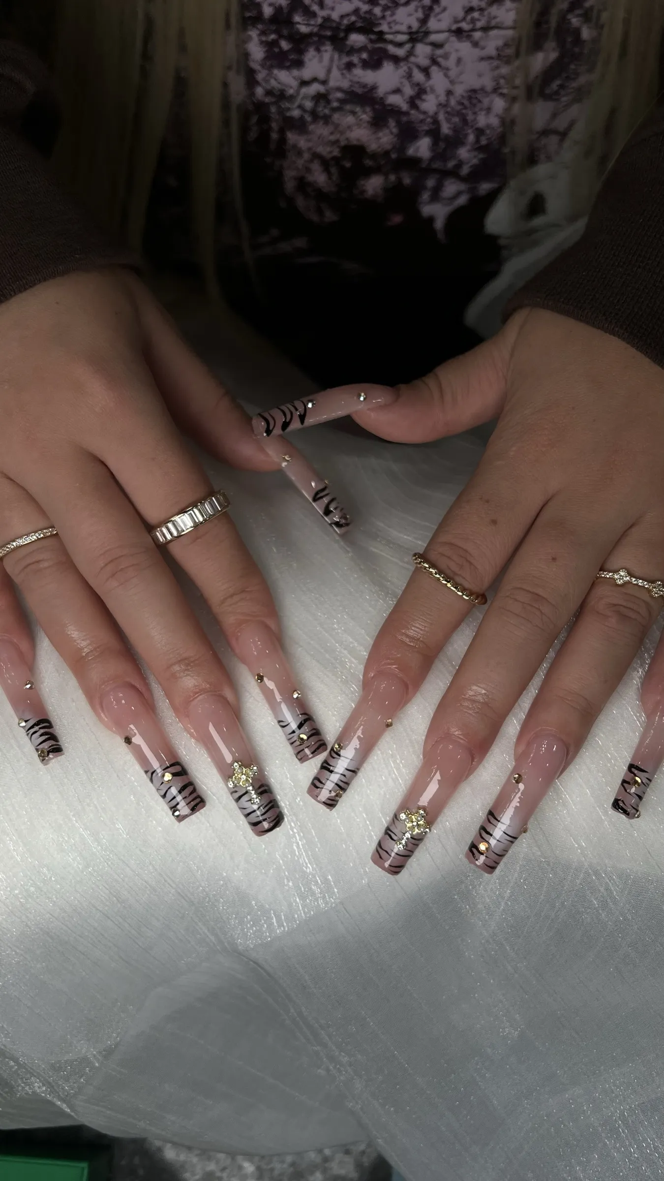 Long square nude nails with black tiger stripe French tips and gold rhinestone accents at Trust Nails & Spa Kissimmee