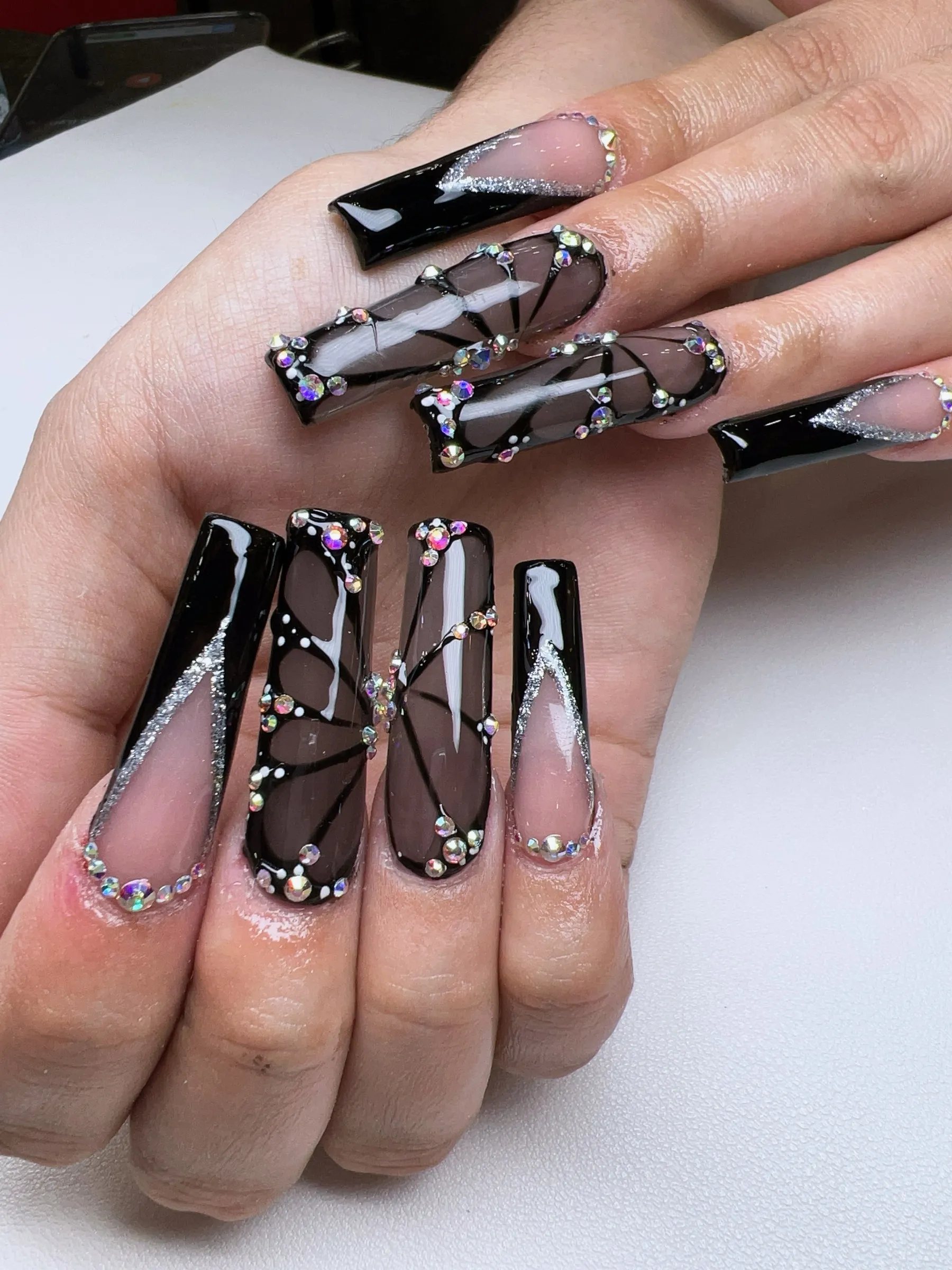 Long square nude and white French tip nails with gold rhinestone butterfly charm accents at Trust Nails & Spa Kissimmee