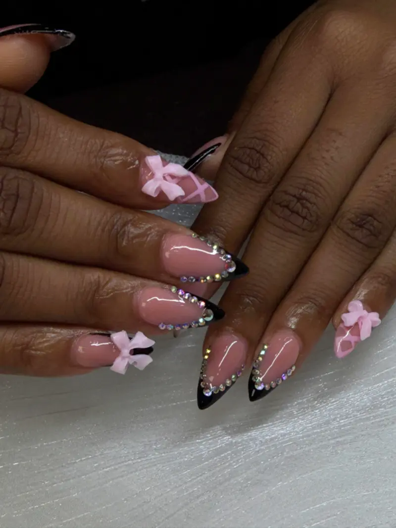Almond medium nails with black French tips, bows and rhinestones